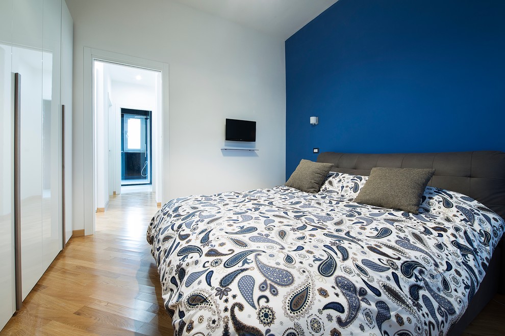 Ejemplo de habitación de invitados actual con paredes azules, suelo de madera clara y suelo marrón