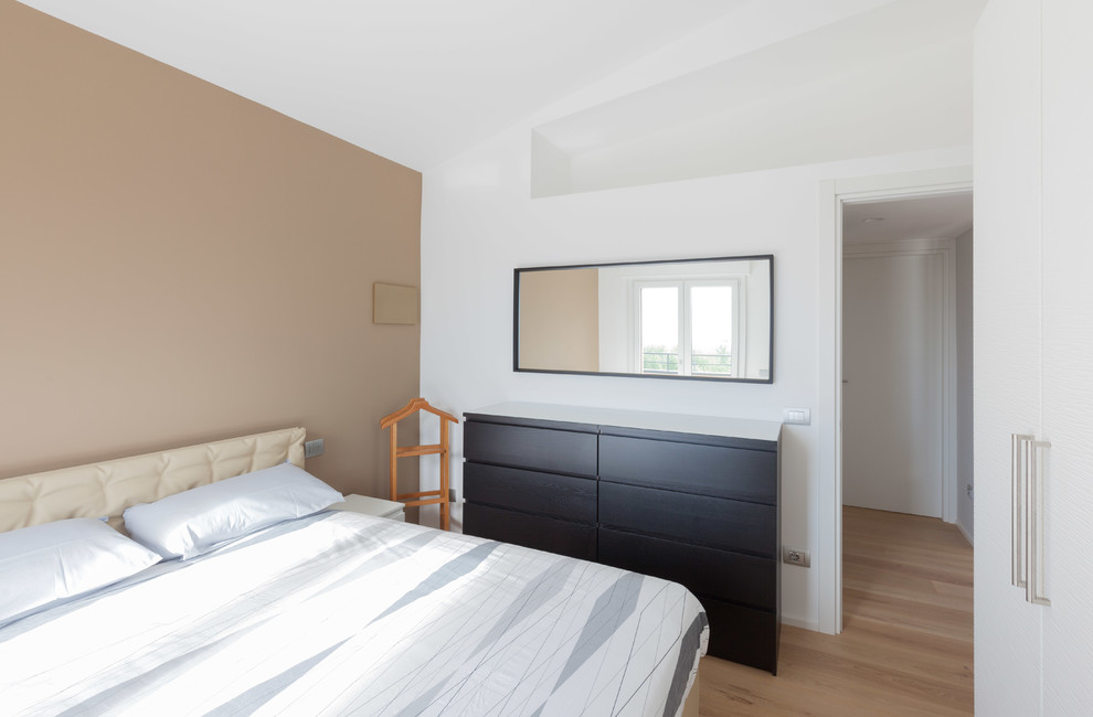 Immagine di una piccola camera matrimoniale design con pareti marroni e parquet chiaro