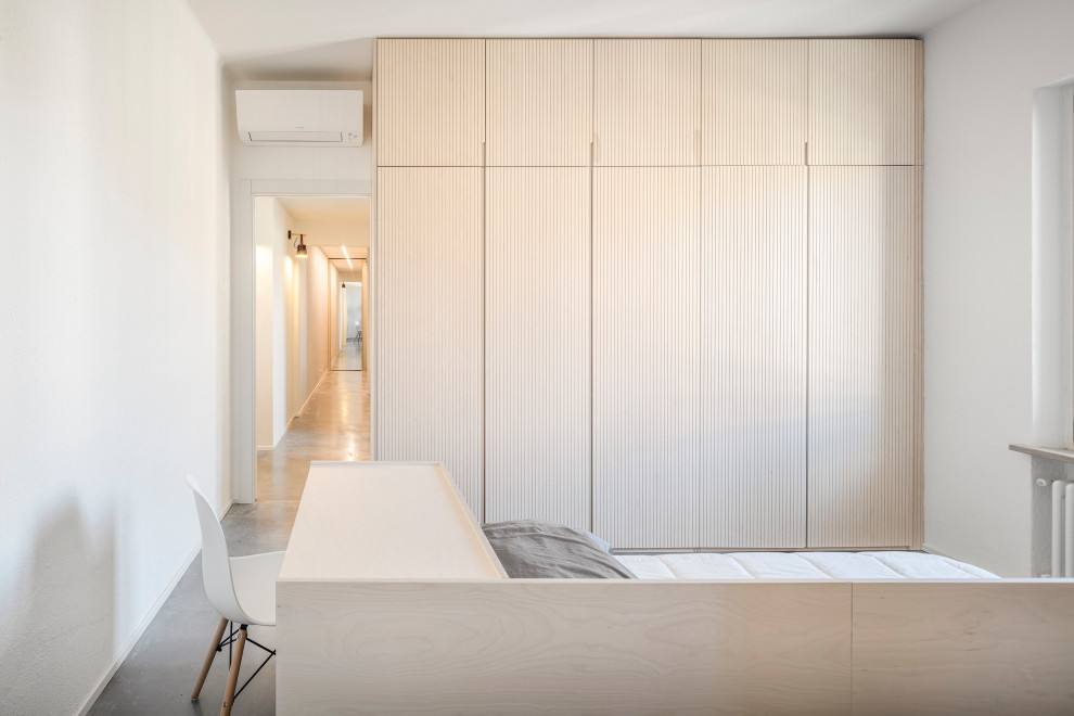 Immagine di una camera degli ospiti stile shabby di medie dimensioni con pareti bianche, pavimento in cemento e pavimento grigio