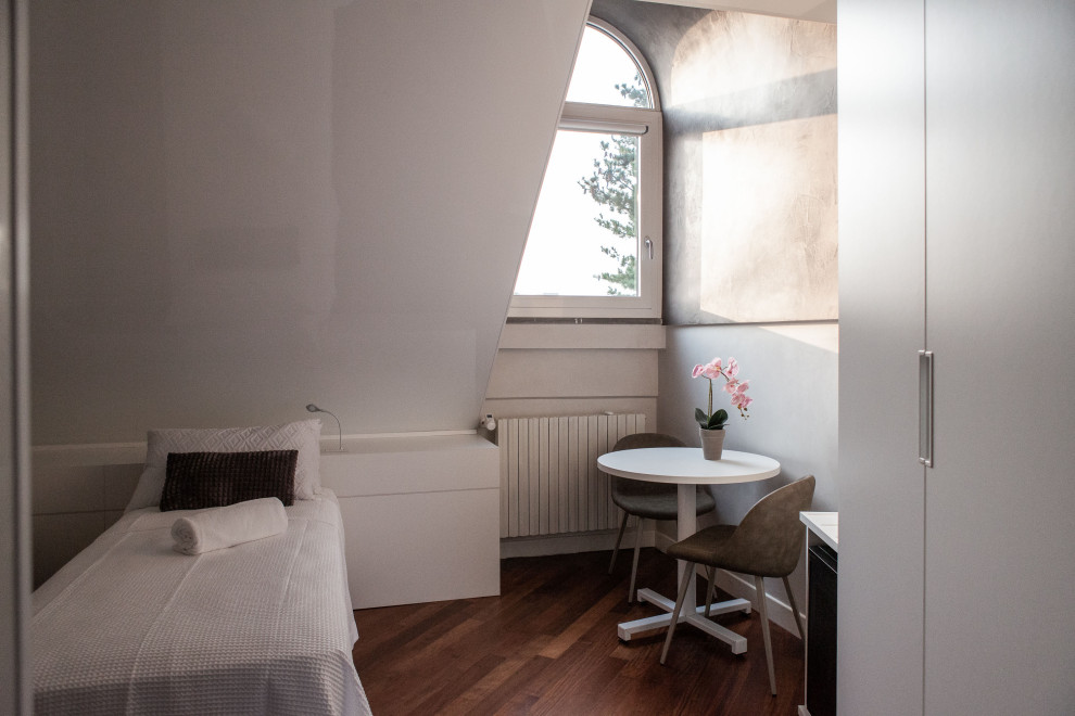 Mittelgroßes Modernes Schlafzimmer mit grauer Wandfarbe, dunklem Holzboden und braunem Boden in Mailand