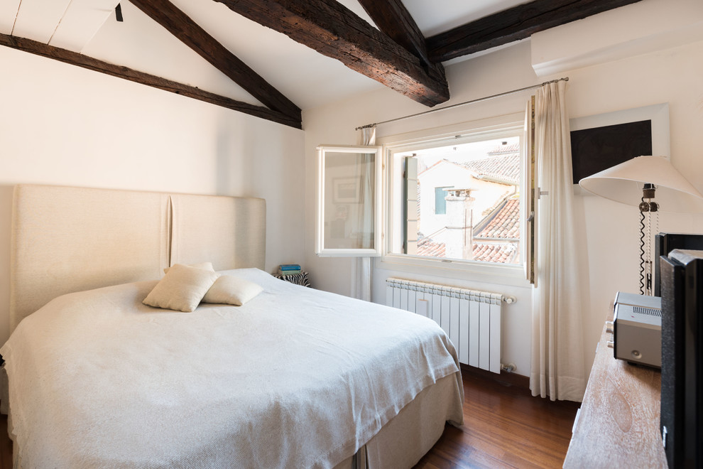 Esempio di una camera degli ospiti mediterranea con pareti bianche, pavimento in legno massello medio e pavimento marrone