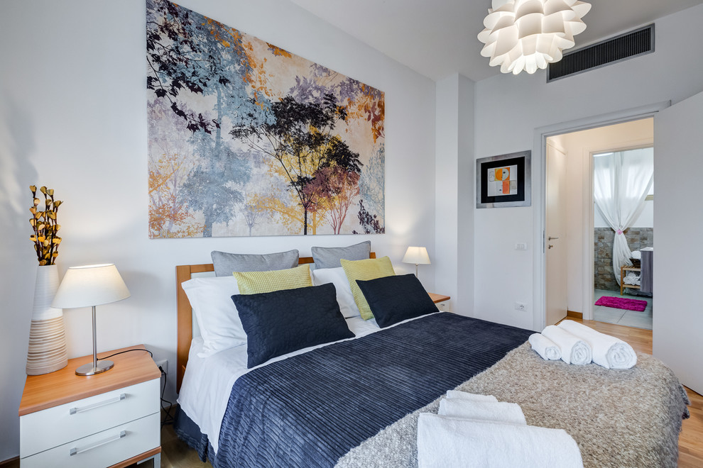 Foto de habitación de invitados actual con paredes blancas y suelo de madera clara
