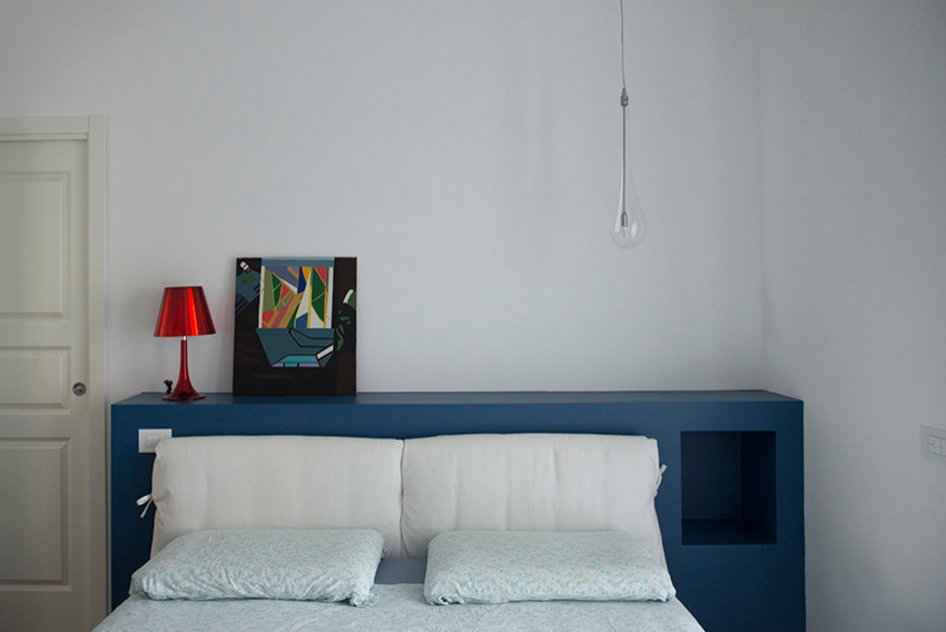 Mittelgroßes Modernes Schlafzimmer mit weißer Wandfarbe, braunem Holzboden, Hängekamin, verputzter Kaminumrandung und braunem Boden in Rom