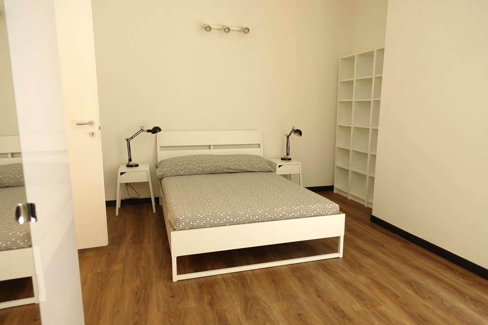 Foto di una camera da letto design di medie dimensioni con pareti bianche e pavimento in laminato