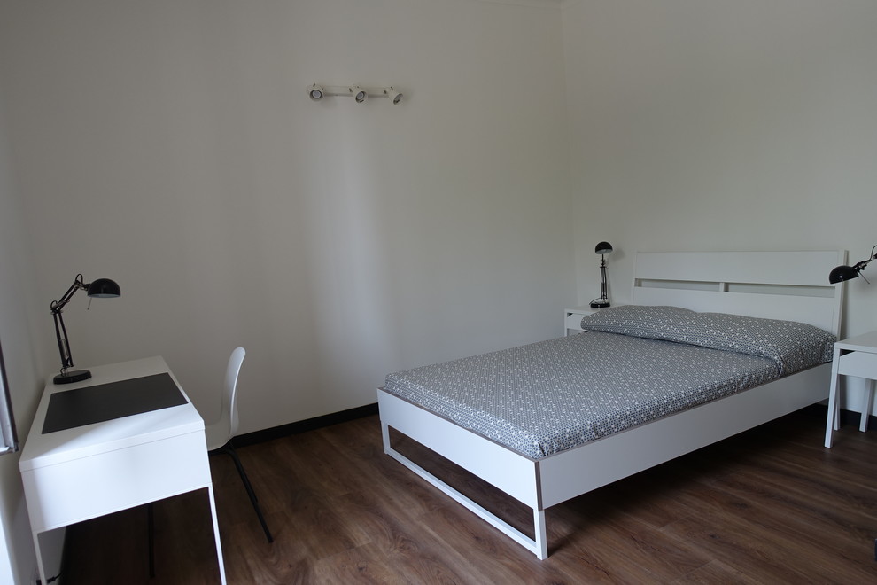 Idee per una camera da letto design di medie dimensioni con pareti bianche e pavimento in laminato