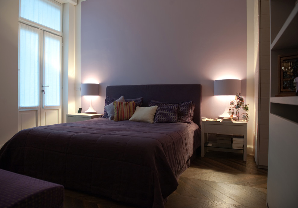 This is an example of a large modern master bedroom in Milan with purple walls, dark hardwood flooring, no fireplace and brown floors.