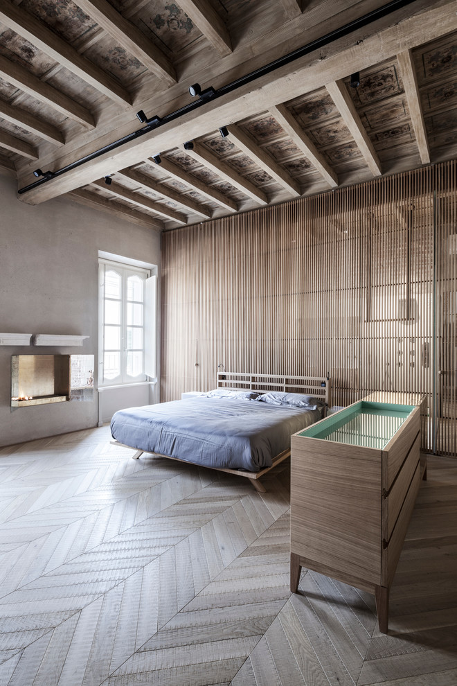 На фото: большая хозяйская спальня в современном стиле с серыми стенами, светлым паркетным полом, подвесным камином и фасадом камина из камня с