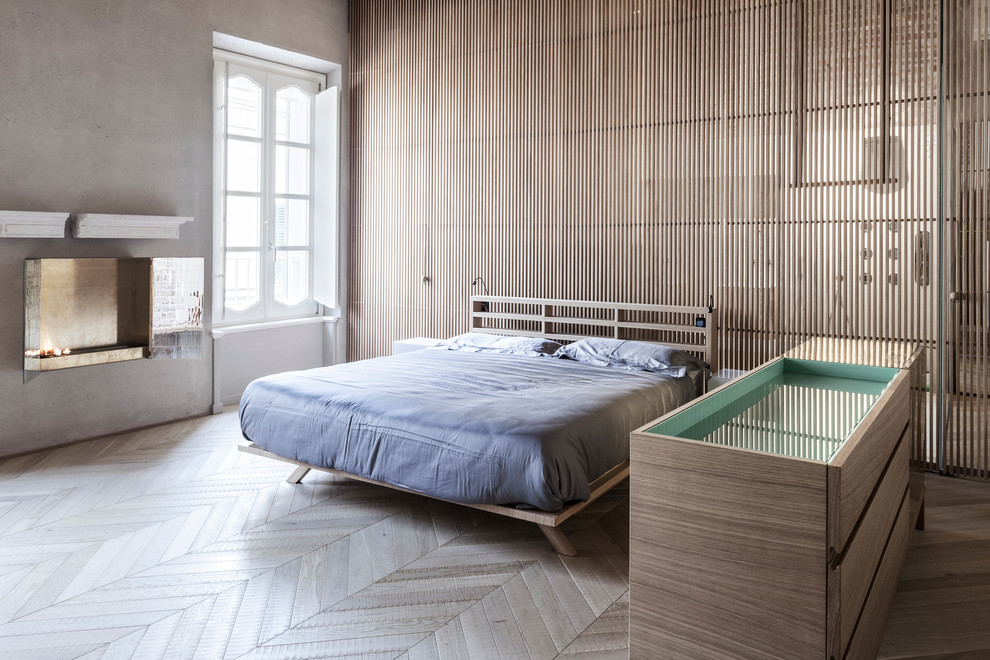Идея дизайна: большая хозяйская спальня в современном стиле с серыми стенами, светлым паркетным полом, подвесным камином и фасадом камина из камня