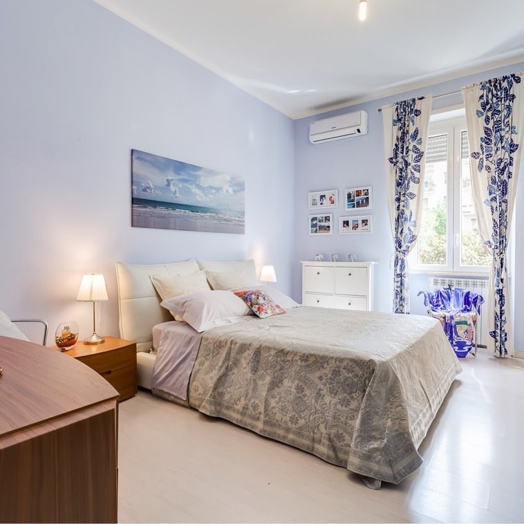Großes Modernes Hauptschlafzimmer mit blauer Wandfarbe, Laminat und beigem Boden in Rom