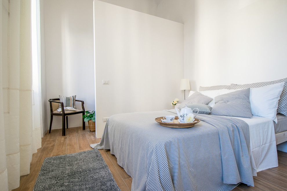 Esempio di una piccola camera degli ospiti design con pareti bianche, pavimento in legno massello medio e pavimento marrone