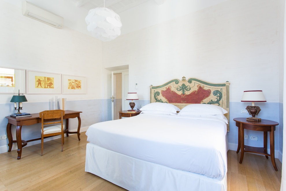Mediterranean bedroom in Rome with blue walls, light hardwood flooring and beige floors.