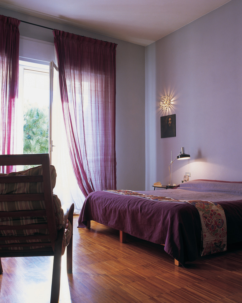 Exemple d'une grande chambre parentale éclectique avec un mur violet, parquet foncé et un sol marron.