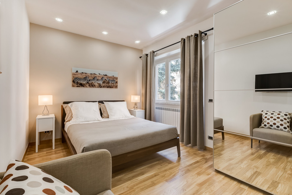 Diseño de dormitorio principal actual con paredes beige y suelo de madera clara