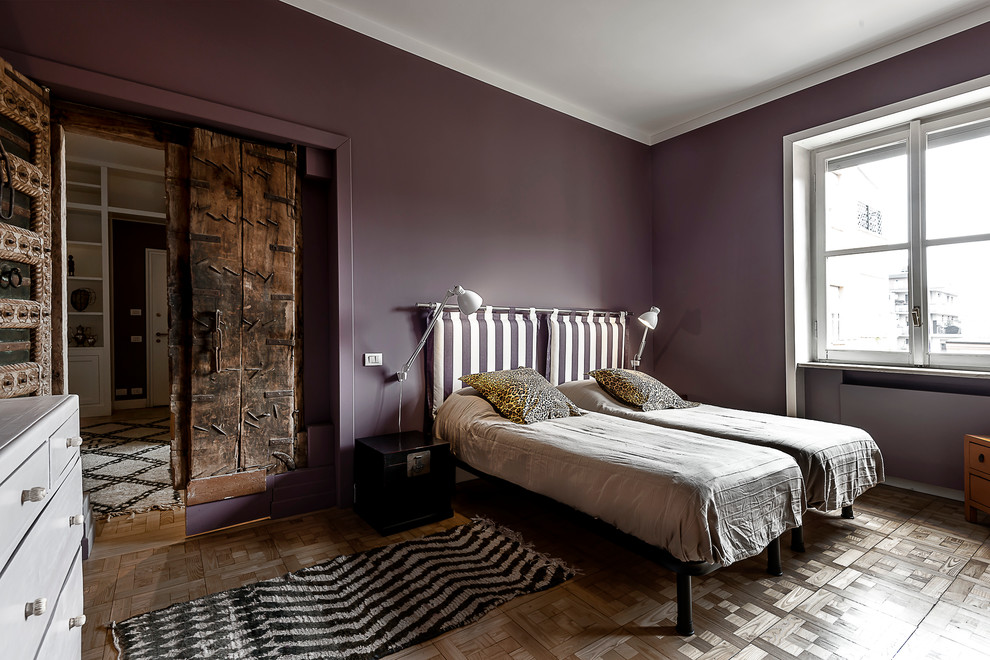 Immagine di una camera da letto bohémian con pareti grigie, pavimento in legno massello medio e cornice del camino in intonaco