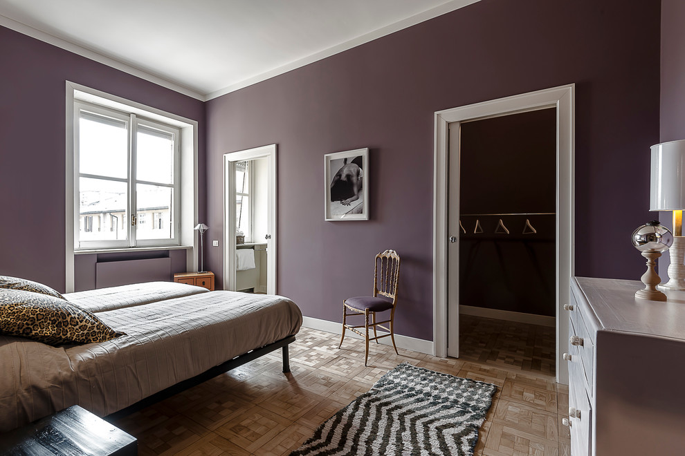 Aménagement d'une chambre éclectique avec un mur violet, un sol en bois brun et un manteau de cheminée en plâtre.