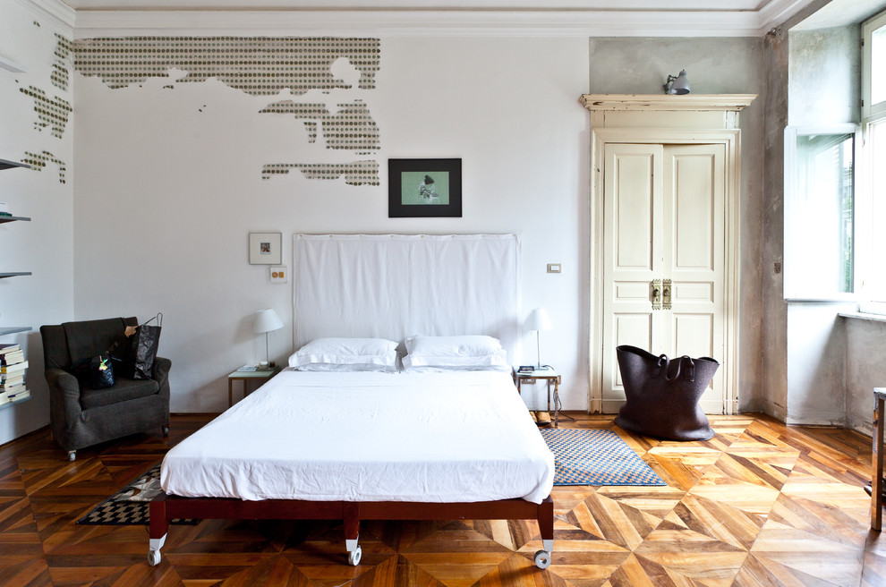 Immagine di una grande camera matrimoniale boho chic con pareti bianche e pavimento in legno massello medio