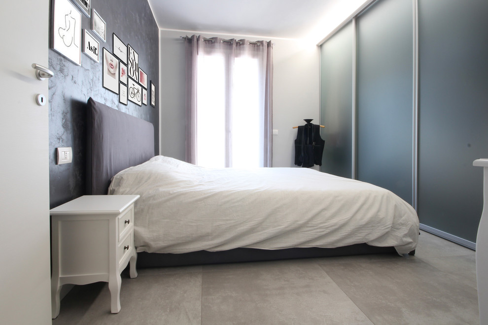 Imagen de dormitorio principal minimalista grande con paredes grises, suelo de baldosas de cerámica, estufa de leña y suelo gris