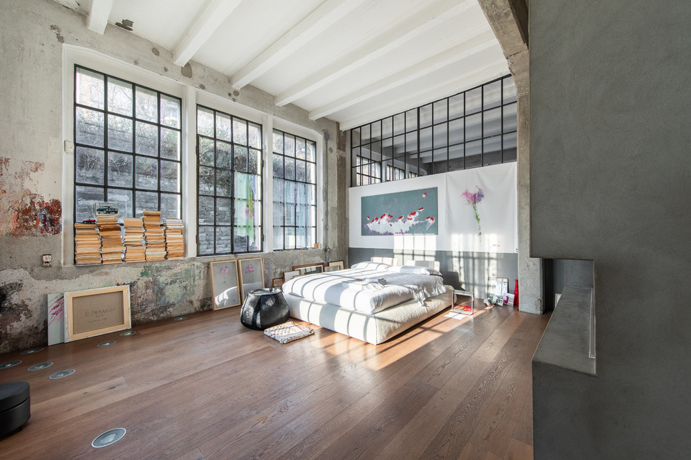 Imagen de dormitorio industrial con paredes grises, suelo de madera en tonos medios y suelo marrón