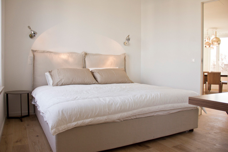 Photo of a small contemporary bedroom in Milan with white walls and medium hardwood flooring.