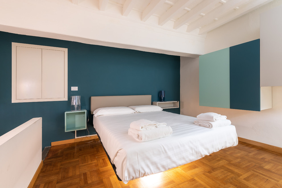 Ispirazione per una piccola camera matrimoniale minimalista con pareti blu, parquet chiaro e pavimento marrone
