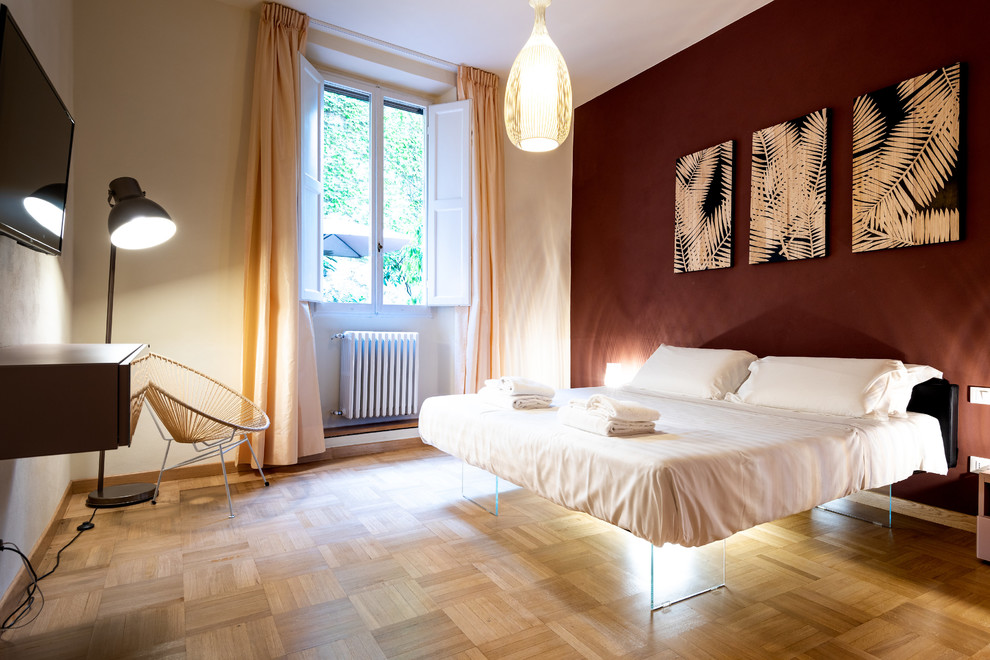Ejemplo de dormitorio principal minimalista de tamaño medio con paredes rojas, suelo de madera en tonos medios y suelo marrón