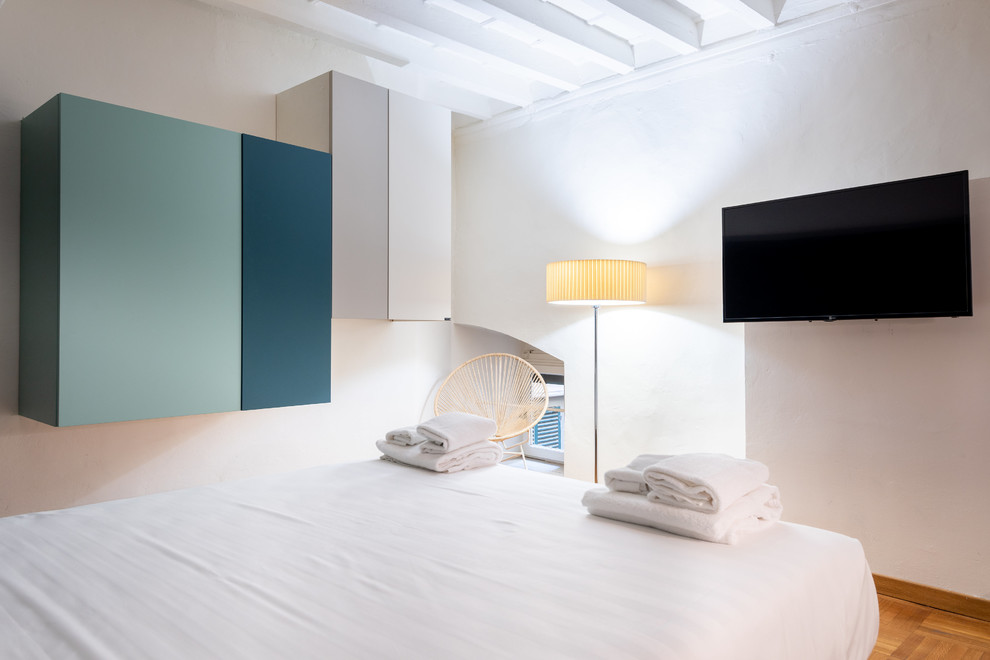 Kleines Modernes Hauptschlafzimmer mit blauer Wandfarbe, hellem Holzboden und braunem Boden in Florenz