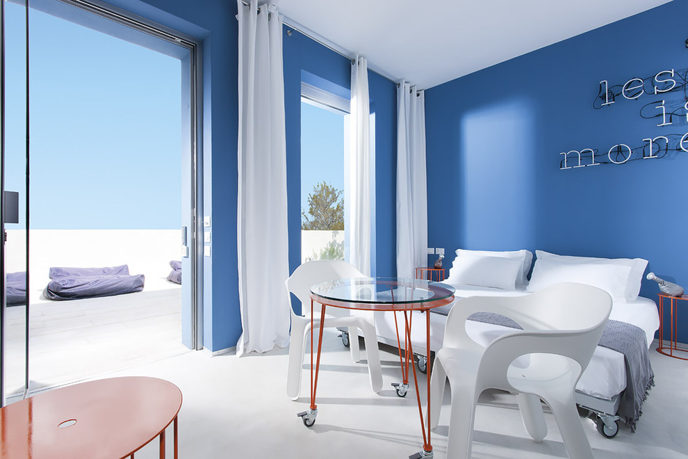 Imagen de dormitorio principal contemporáneo grande con paredes azules y suelo de cemento