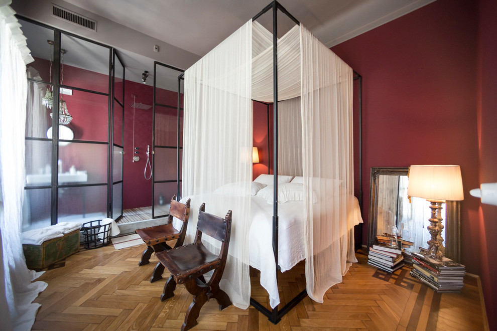 Imagen de dormitorio principal tradicional renovado de tamaño medio sin chimenea con paredes rojas, suelo de madera en tonos medios y suelo marrón