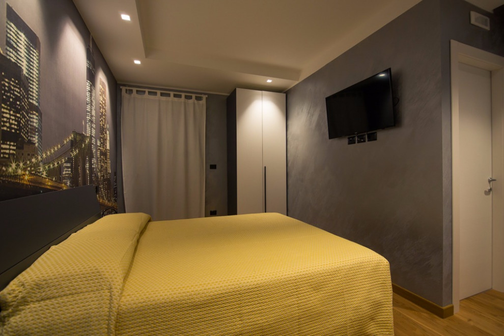 Imagen de habitación de invitados minimalista pequeña con paredes multicolor, suelo de madera clara, suelo marrón y papel pintado