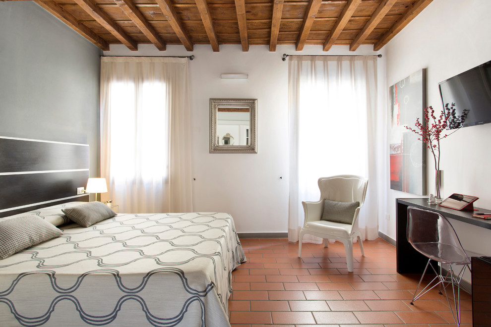 На фото: гостевая спальня среднего размера, (комната для гостей) в современном стиле с белыми стенами, полом из терракотовой плитки и оранжевым полом с