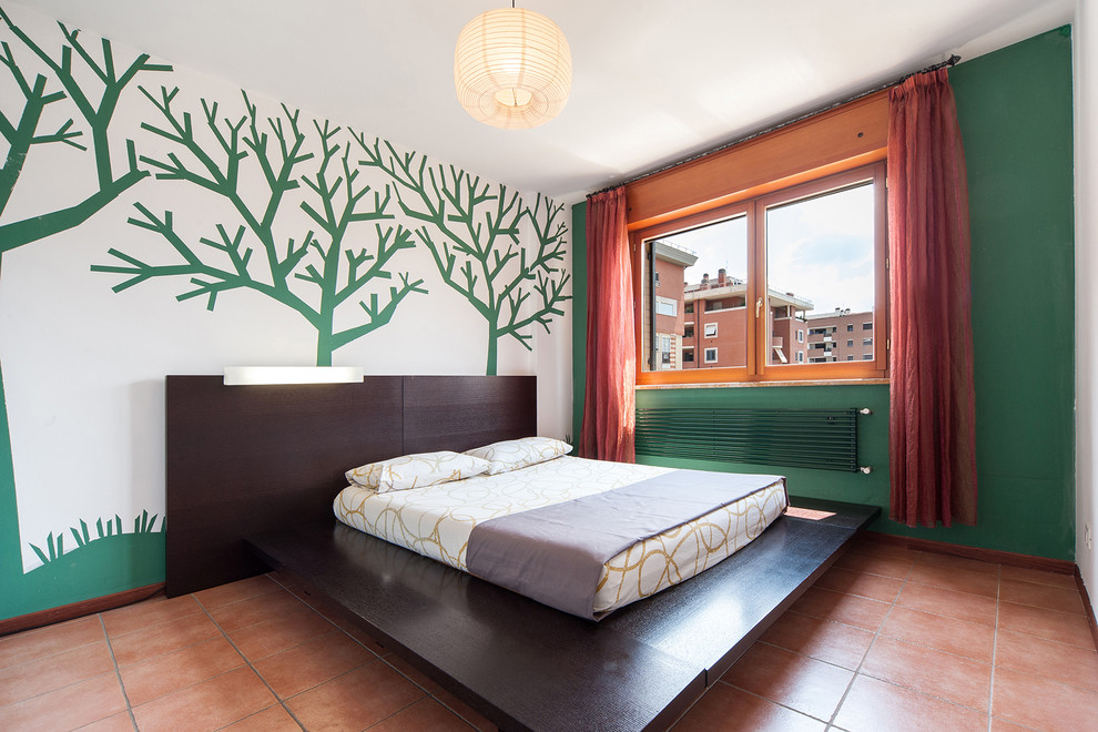 Réalisation d'une chambre parentale design avec un mur vert et tomettes au sol.
