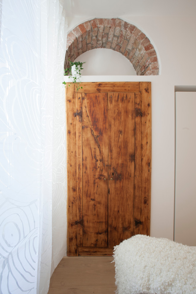 Diseño de dormitorio principal bohemio pequeño con paredes blancas, suelo de madera clara y suelo beige