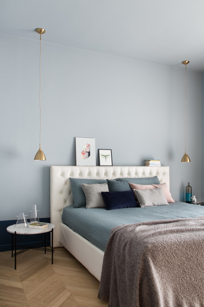 Idée de décoration pour une chambre parentale design avec un mur bleu, aucune cheminée et parquet clair.
