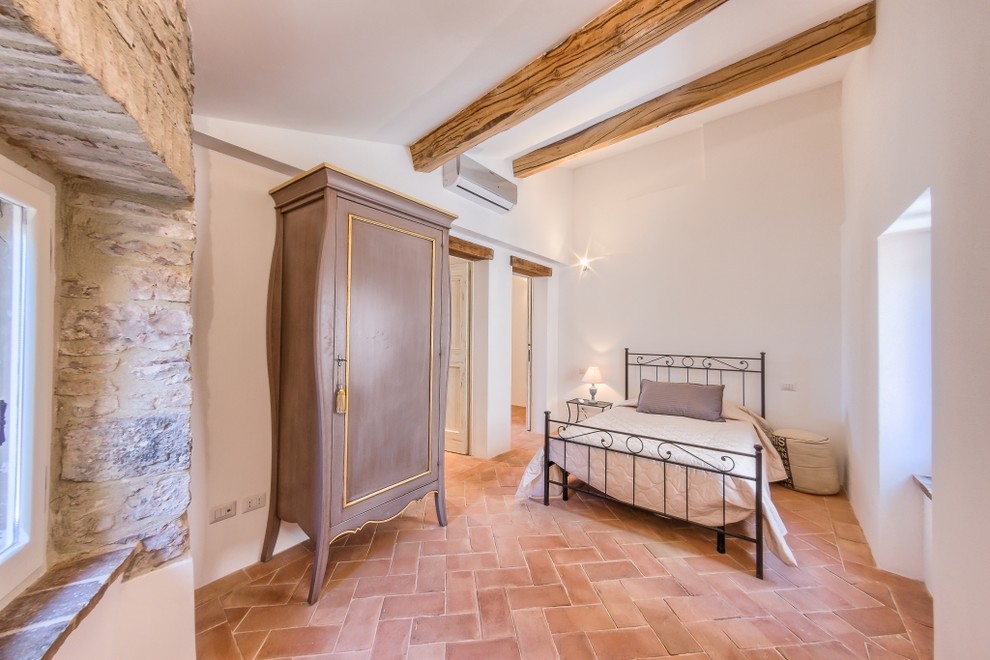 Exemple d'une chambre d'amis méditerranéenne de taille moyenne avec un mur blanc et tomettes au sol.