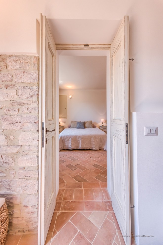 На фото: хозяйская спальня среднего размера в средиземноморском стиле с белыми стенами и полом из терракотовой плитки с