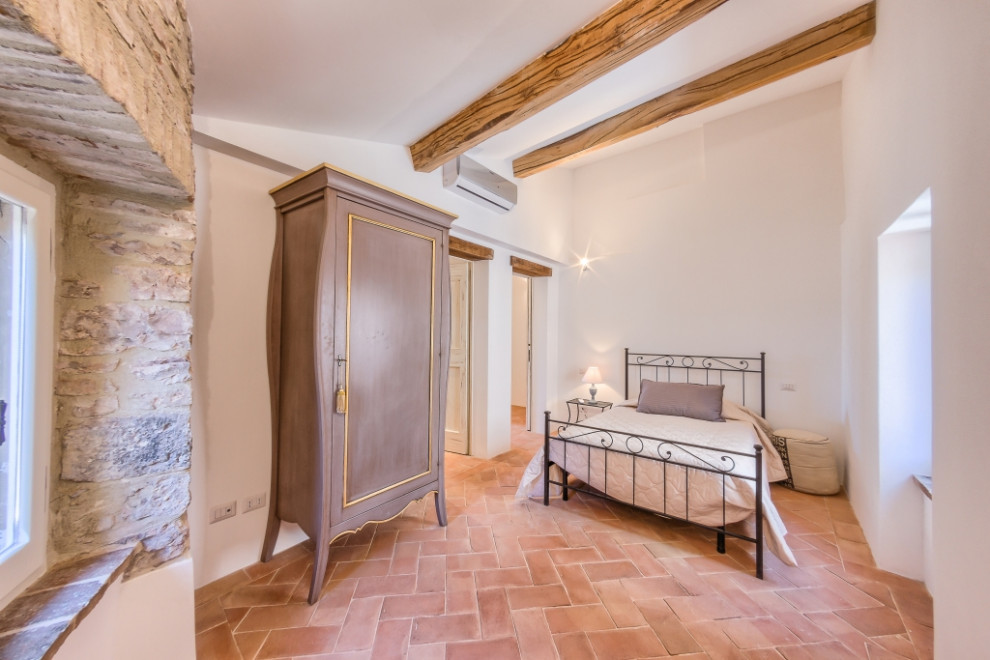 Esempio di una camera degli ospiti shabby-chic style con pareti bianche e pavimento in terracotta