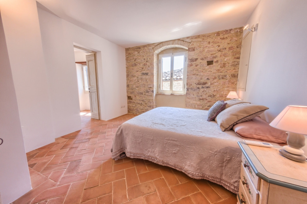 Foto de dormitorio principal romántico con paredes blancas y suelo de baldosas de terracota