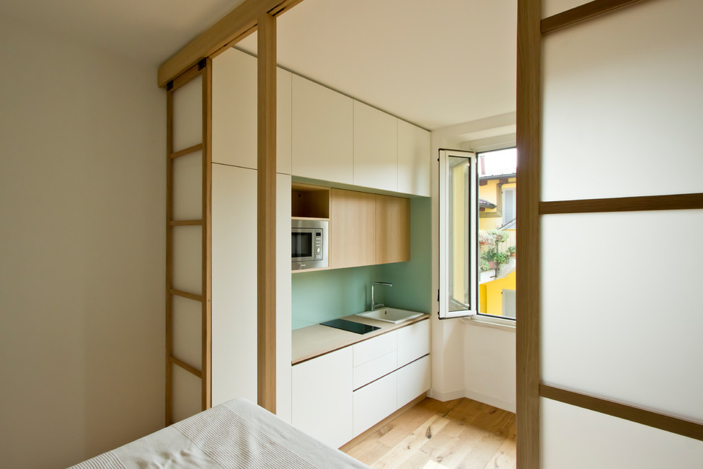 Ispirazione per una piccola camera da letto stile loft scandinava con pareti bianche, parquet chiaro e pavimento marrone