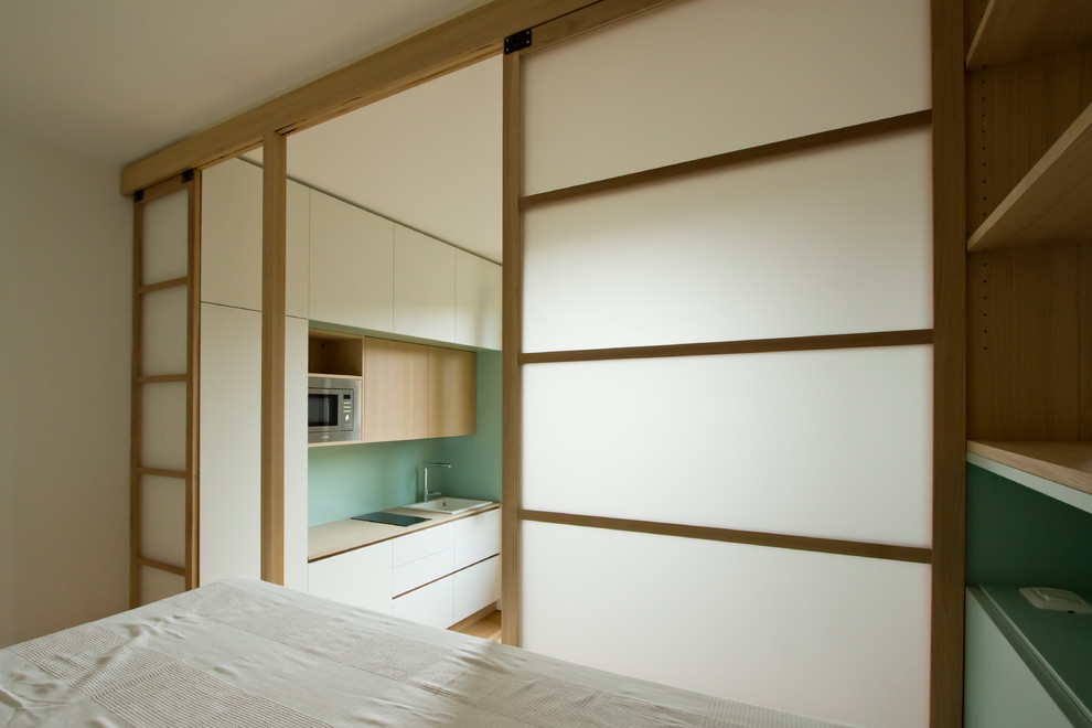 Ejemplo de dormitorio tipo loft nórdico pequeño con suelo de madera clara y suelo marrón