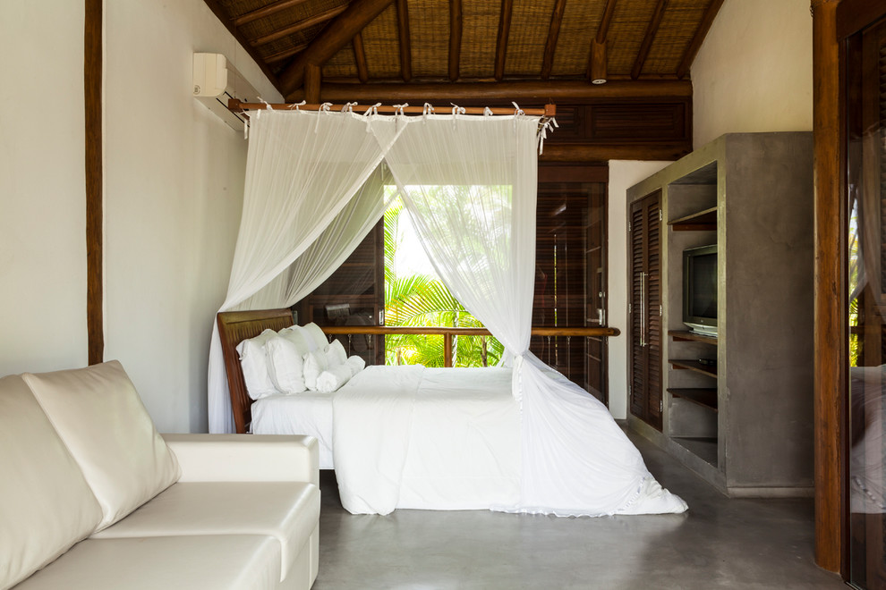 Foto di una camera da letto tropicale con pareti bianche, pavimento in cemento e pavimento grigio