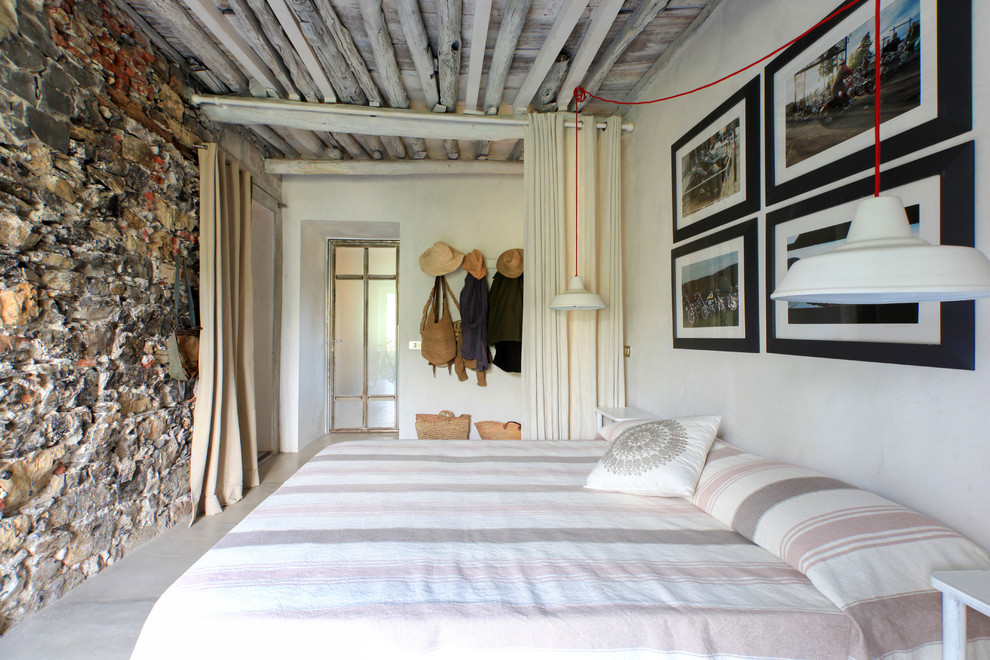 На фото: гостевая спальня (комната для гостей) в средиземноморском стиле с белыми стенами, бетонным полом, серым полом и зонированием шторами