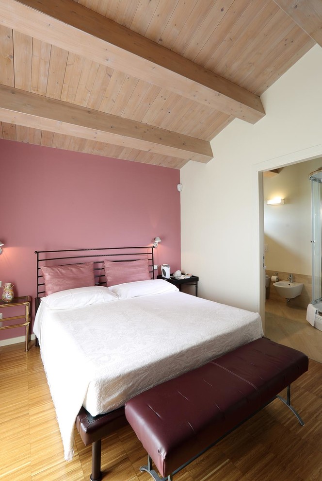Modelo de dormitorio principal actual de tamaño medio con paredes rosas, suelo de madera en tonos medios y suelo marrón