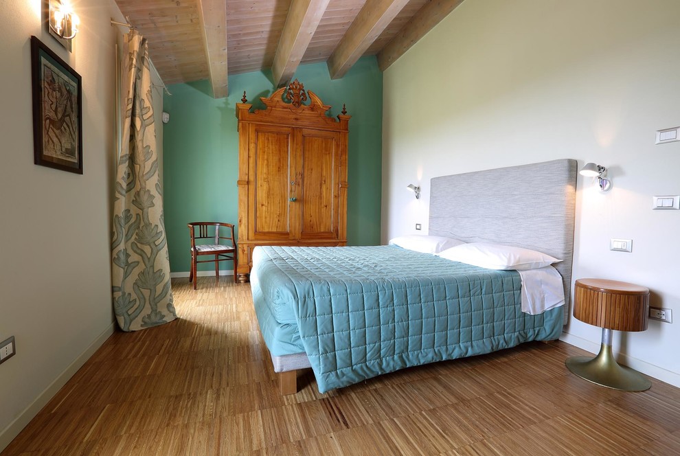 Mittelgroßes Modernes Hauptschlafzimmer mit grüner Wandfarbe, braunem Holzboden und braunem Boden in Bologna