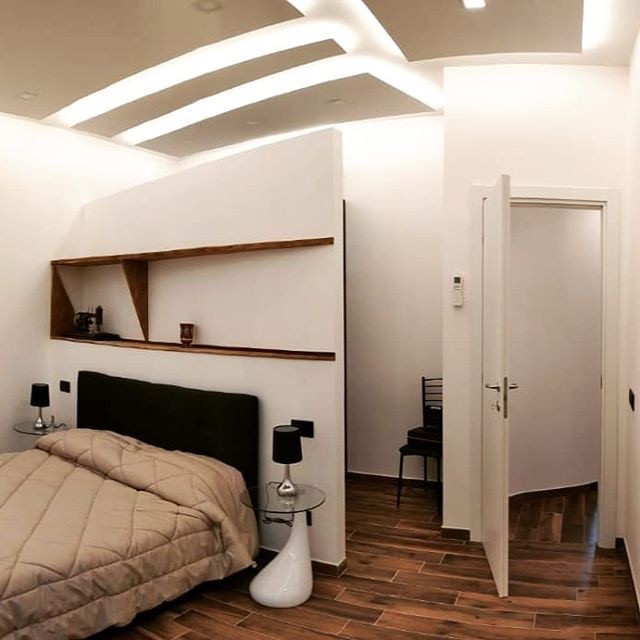 Exemple d'une grande chambre parentale tendance avec un mur blanc, un sol en carrelage de porcelaine et un sol marron.