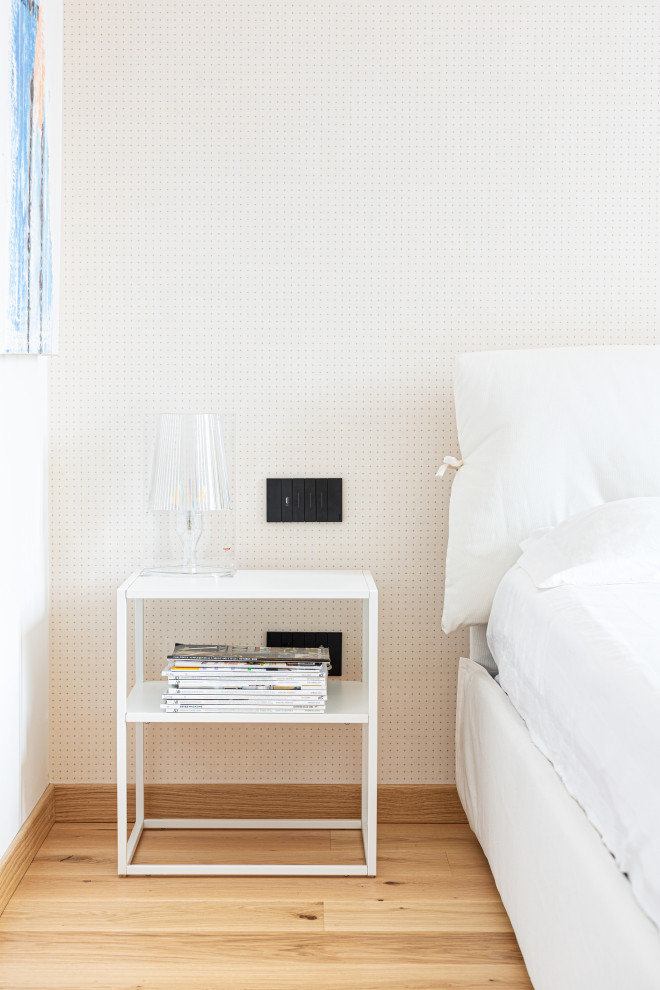 Modelo de dormitorio principal nórdico de tamaño medio con paredes blancas, suelo de madera clara, bandeja y papel pintado