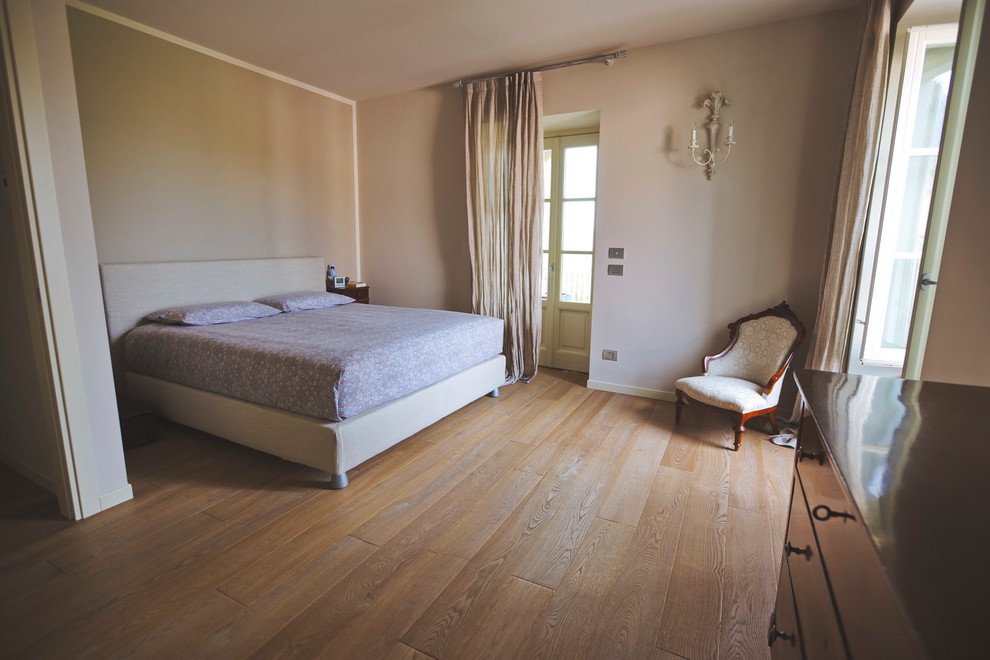 Imagen de dormitorio principal minimalista de tamaño medio sin chimenea con paredes marrones, suelo de madera clara y suelo marrón