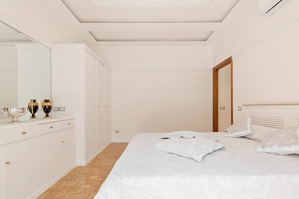 Mittelgroßes Nordisches Hauptschlafzimmer ohne Kamin mit weißer Wandfarbe, braunem Holzboden und beigem Boden in Rom