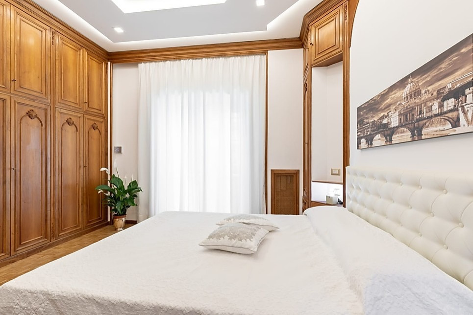 Großes Klassisches Hauptschlafzimmer ohne Kamin mit weißer Wandfarbe, braunem Holzboden und braunem Boden in Rom