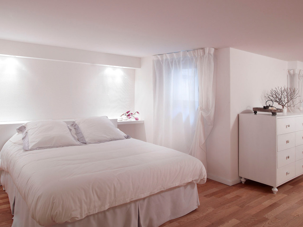 Immagine di una piccola camera matrimoniale design con pareti bianche, parquet chiaro, stufa a legna e pavimento marrone