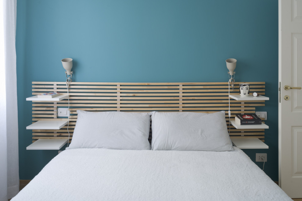 Skandinavisches Hauptschlafzimmer mit blauer Wandfarbe und hellem Holzboden in Mailand